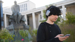 Молодой человек с телефоном в руках у памяткика