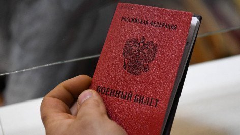 Мужчина держит военный билет в военном комиссариате