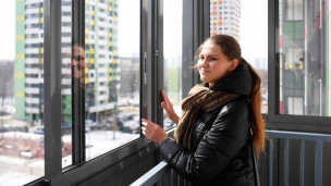 Женщина на лоджии в многоэтажном жилом доме
