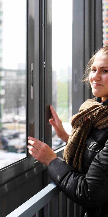 Женщина на лоджии в многоэтажном жилом доме