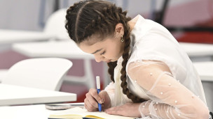 школьница за партой пишет в тетради