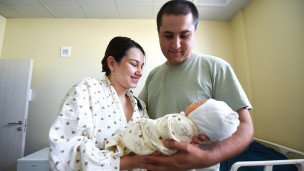 Молодые родители с новорожденным ребенком