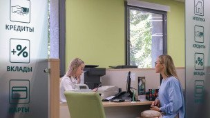Сотрудница банка и посетительница рядом с надписью "кредиты"