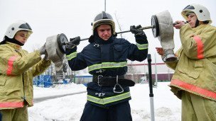 Пожарный во время профессионального конкурса поднимает штангу