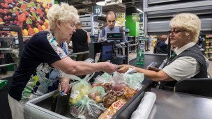 Пожилая женщина и кассир на кассе продуктового магазина