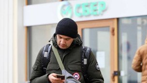 Мужчина с телефоном около банка
