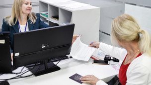 Сотрудница федеральной налоговой службы принимает документ у женщины