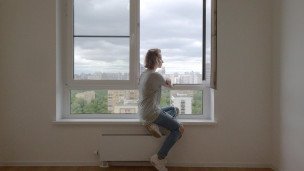 Девушка сидит на подоконнике в квартире