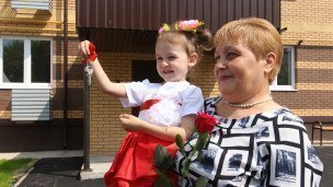 Девочка на руках у женщины держит ключи от квартиры