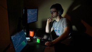 Мужчина за компьютером в темной комнате