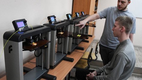Студент и преподаватель в кабинете по изготовлению прототипов из пластика и дерева на 3D принтерах
