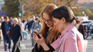 Девушки на улице смотрят видео на телефоне