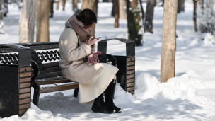 Девушка сидит с телефоном в парке