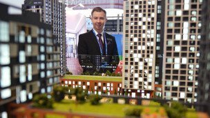 Мужчина в костюме около макета жилого комплекса