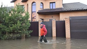 мужчина на территории подтопления возле жилого дома