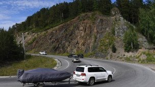 Автомобиль с прицепом с моторной лодкой едет по трассе 