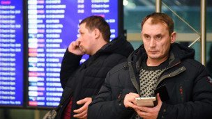 Пассажиры в аэропорту говорят по телефону