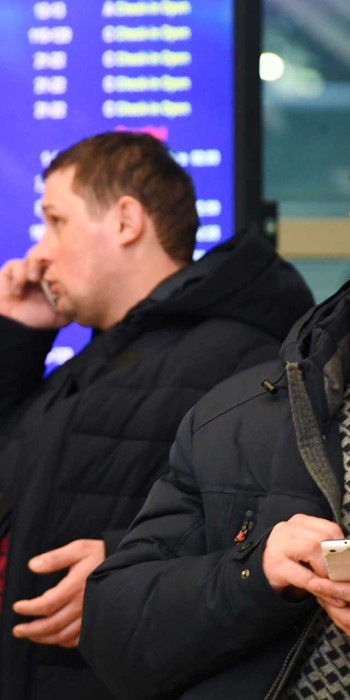 Пассажиры в аэропорту говорят по телефону