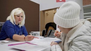 Сотрудница помогает посетительнице заполнять документы