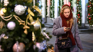 Девушка с телефоном у новогодней ели 