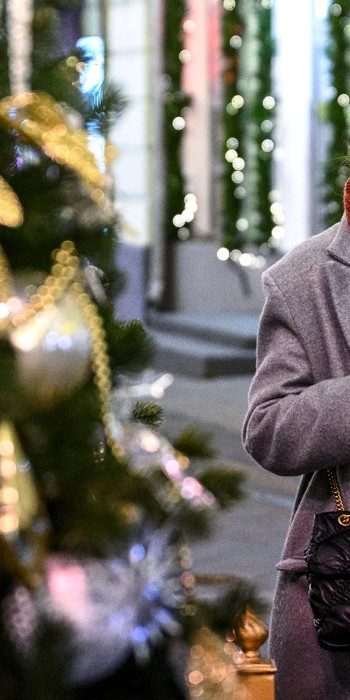 Девушка с телефоном у новогодней ели 