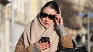  Городская жительница в солнцезащитных очках со смартфоном