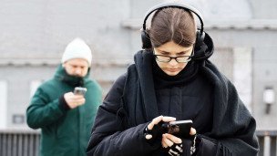Девушка с телефоном в наушниках на улице