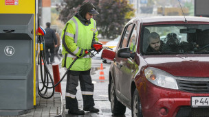 Сотрудник АЗС заправляет автомобиль