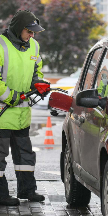 Сотрудник АЗС заправляет автомобиль