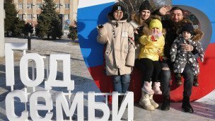 Люди во время новогодних гуляний рядом с логотипом Год семьи