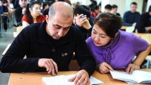 Мигранты во время экзамена на знание русского языка в миграционном центре 