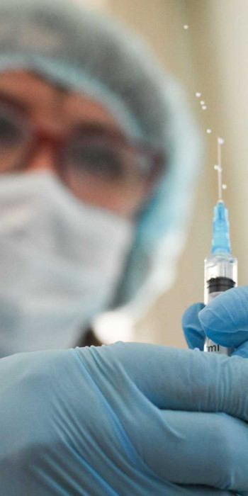 Врач держит в руках шприц с вакциной