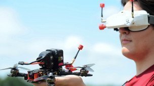 Студент технического университета в FPV очках держит в руках дрон перед испытательными полетами