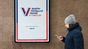 Женщина проходит мимо агитационного предвыборного баннера