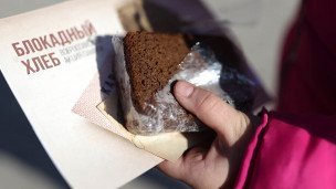 Человек держит хлеб во время всероссийской акции памяти "Блокадный хлеб"