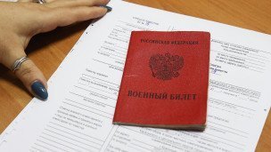 Военный билет и повестка на столе военного комиссариата.