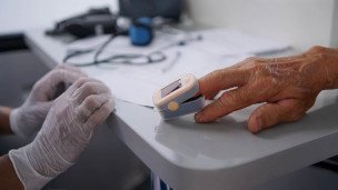 Медик замеряет сатурацию у мужчины в мобильном фельдшерско-акушерском пункте (ФАП) в деревне