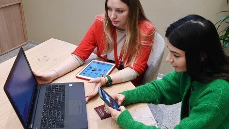 Сотрудница и клиентка заполняют документы на ноутбуке