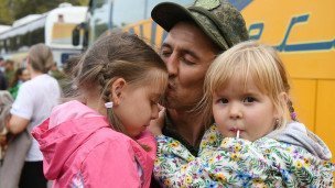 Мужчина в военной форме держит на руках двух девочек