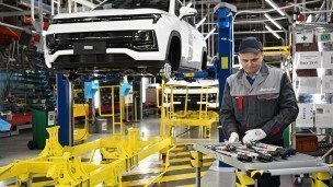 Рабочий за сборкой автомобиля на производственной линии