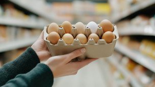 Картонная упаковка с куриными яйцами в руках покупателя 