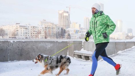 Мужчина зимой на пробежке с собакой