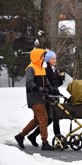 Семейная пара с детской коляской гуляет в парке