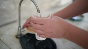 Девушка наливает воду в стакан
