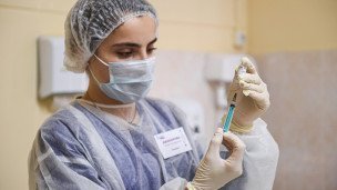 Медицинский работник готовится сделать прививку 