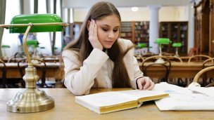 devushka-studentka-chitaet-knigu-v-biblioteke