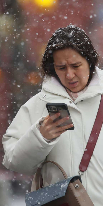 Девушка на улице с телефоном в снежную погоду