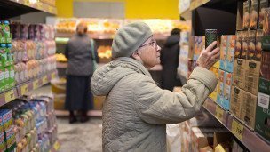 Пожилая женщина в магазине выбирает продукты