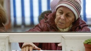 Пенсионерка получает пенсию в кассе