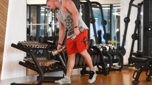 posetitel-v-fitnes-klube-kladet-ganteli-na-stojku